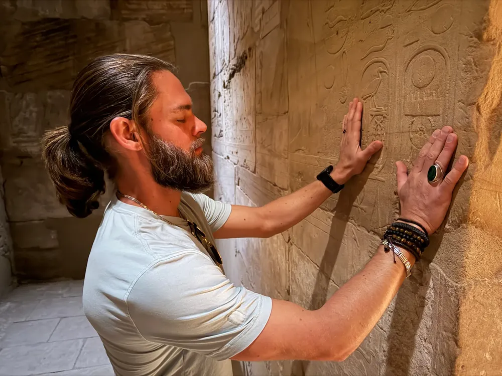 Brandon touching hieroglyphs carved into a temple wall