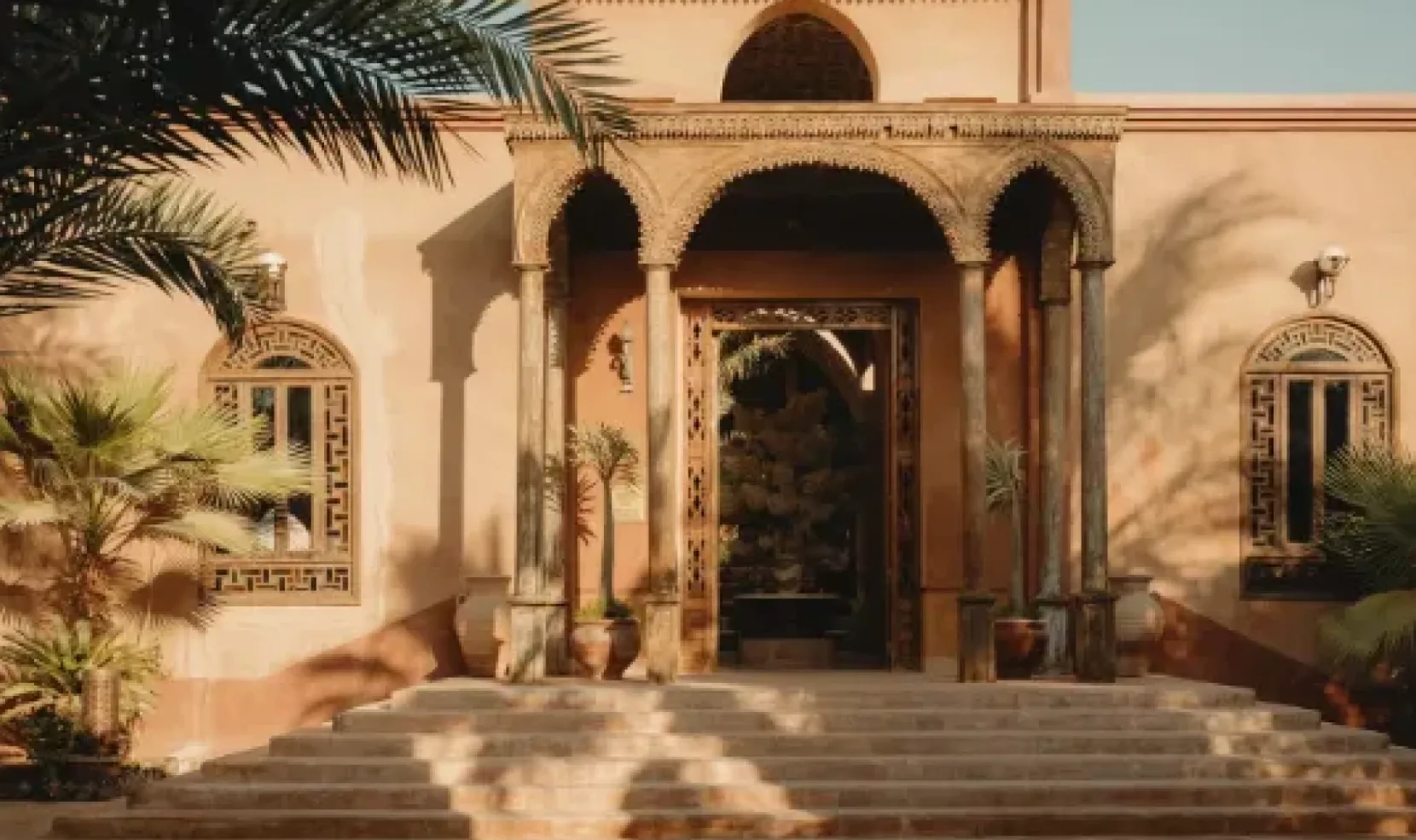 Al Moudira Hotel entrance framed by palm trees in Luxor